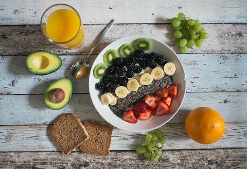 a bowl of fruit and bread with a knife and a glass of juice