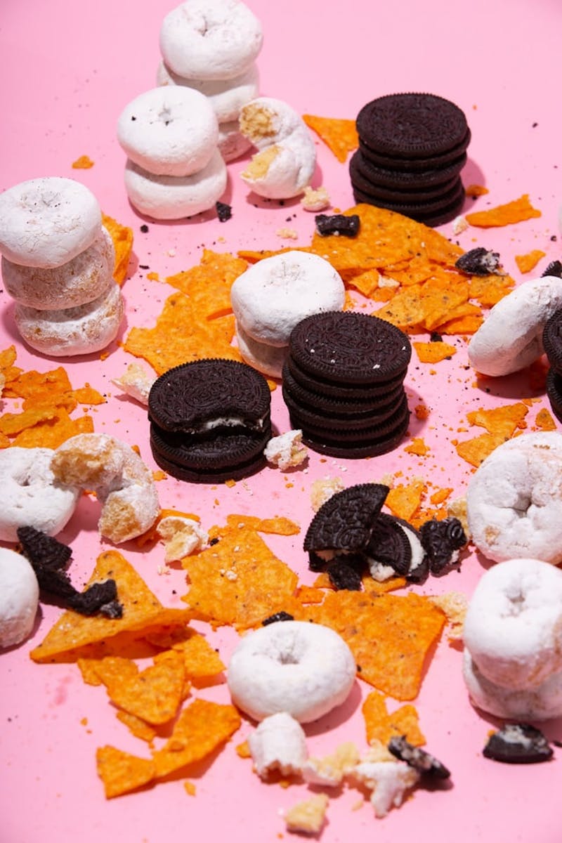 Doritos, Oreos, and donuts displayed on a pink surface