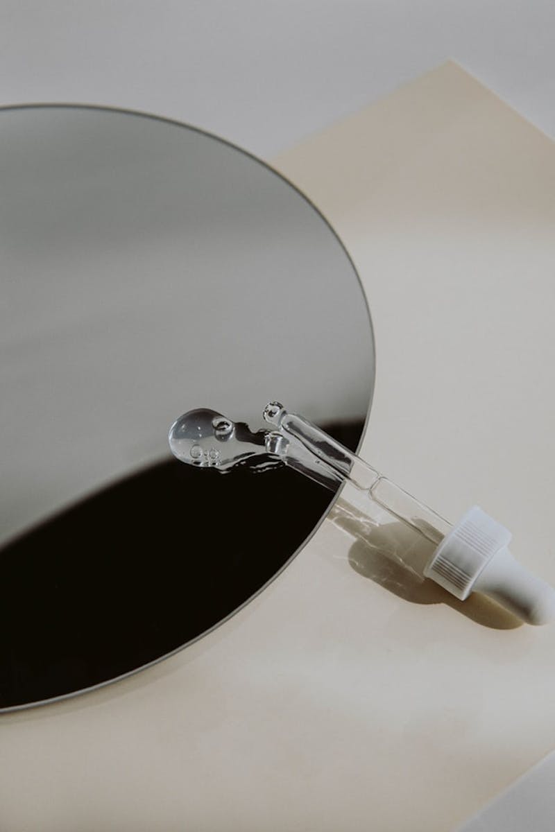 a mirror with a dropper and liquid spilled on the mirror