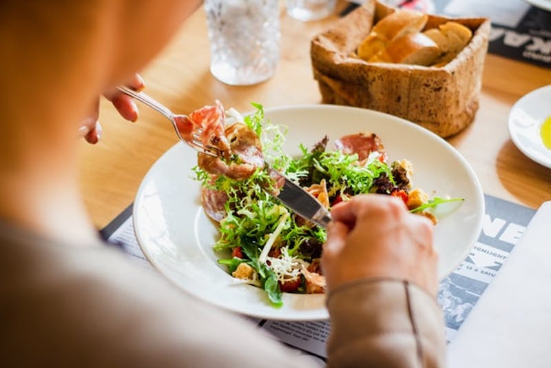 someone is eating a salad with a knife and fork on a plate