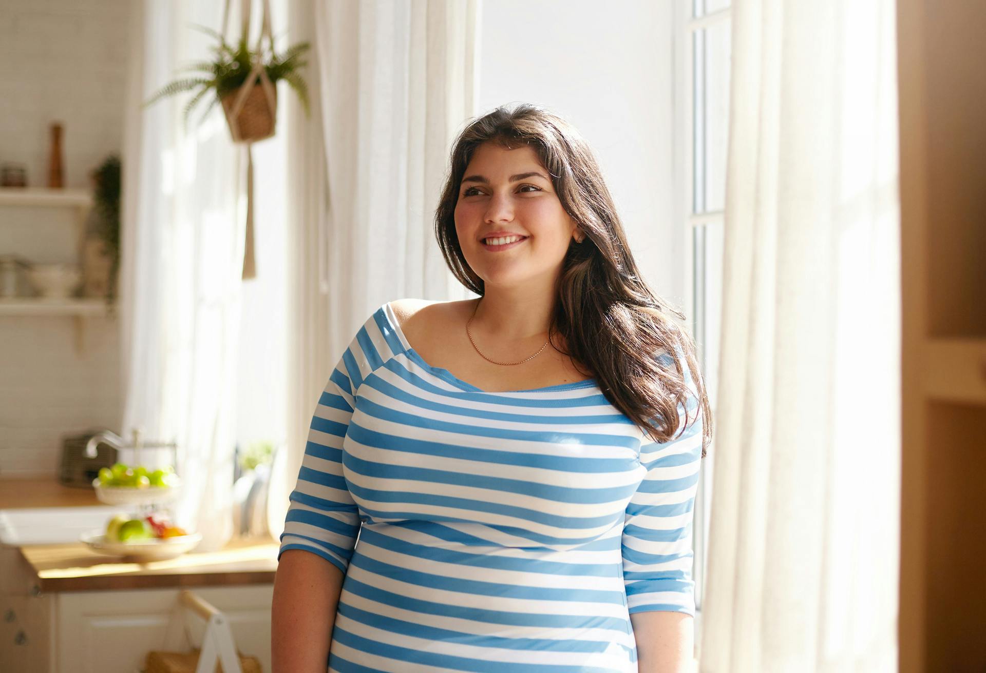 Woman in blue and white striped shirt in front of a window