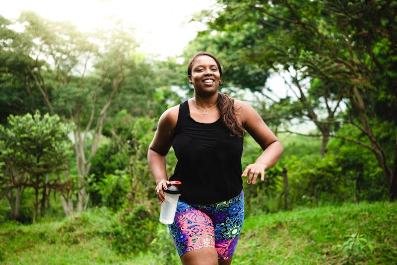 a woman running in a field with a water container