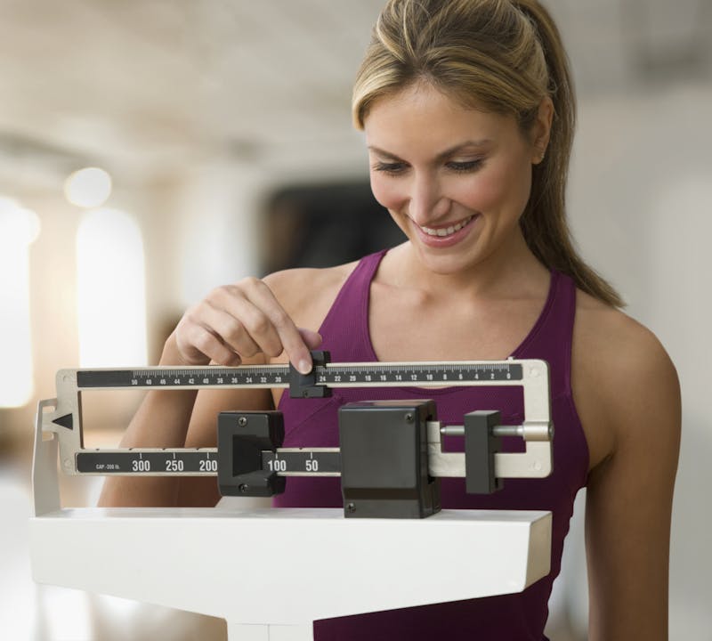 smiling woman adjusting weight scale