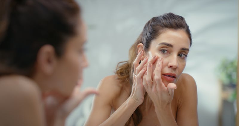 woman looking into mirror and inspecting face