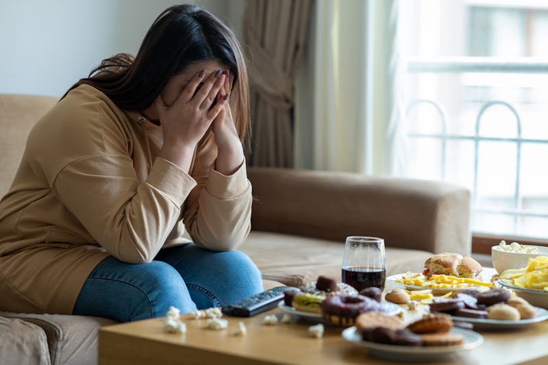 woman holding her head with food in front of her