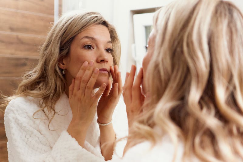 blonde woman looking at herself in the mirror