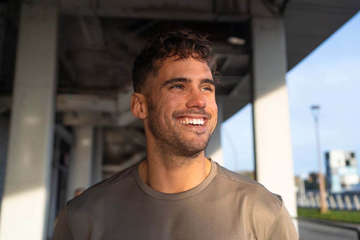 man smiling under a bridge