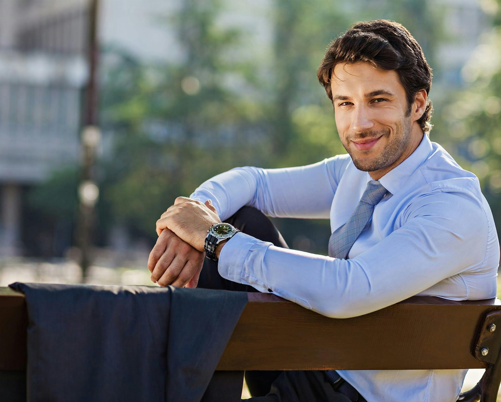 Man in a dress shirt and tie sitting outside