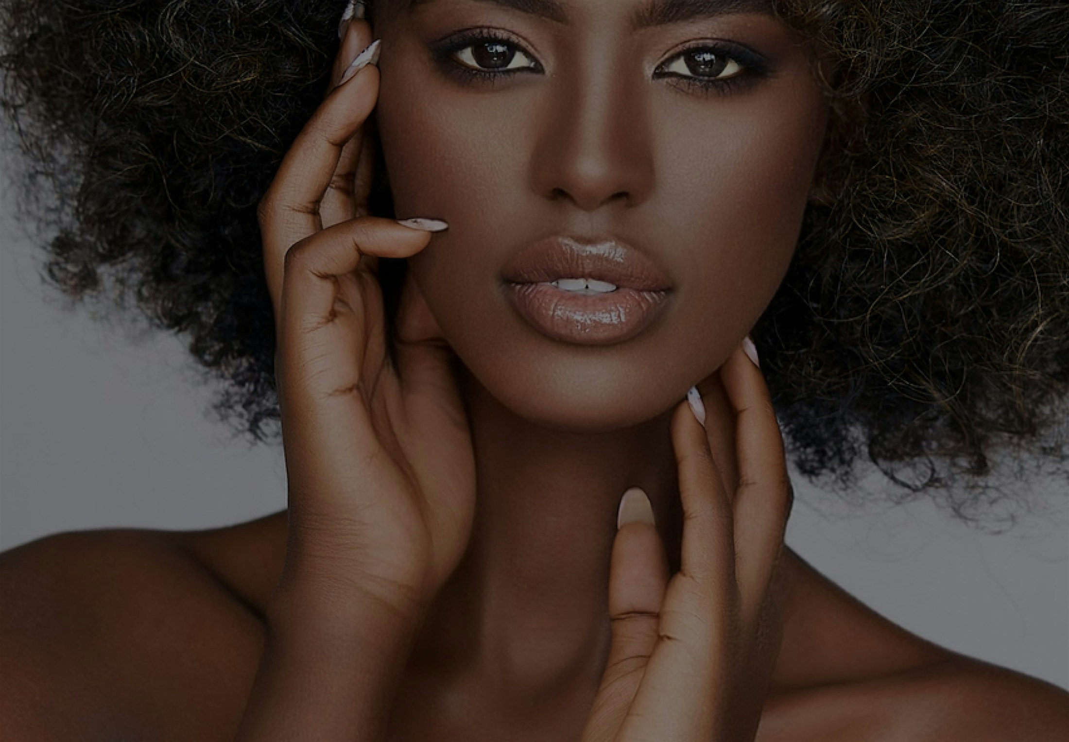 woman with a large afro holding her hand to her face