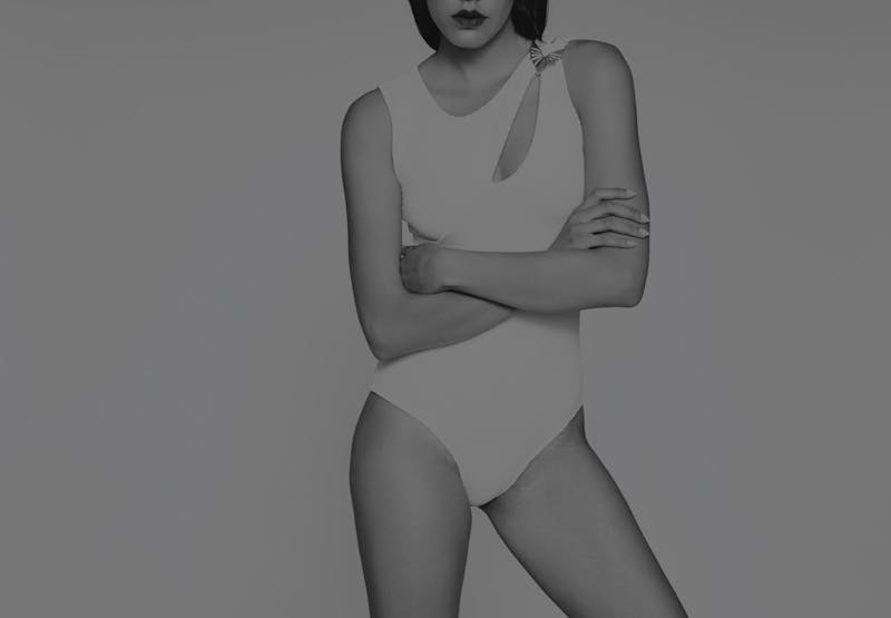 woman in a white bodysuit posing with her arms crossed