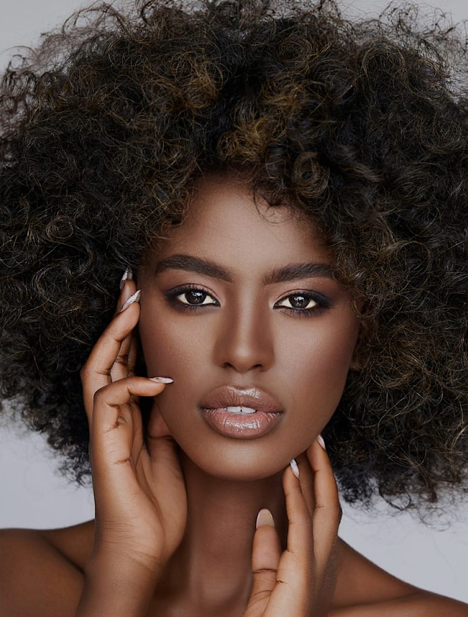 woman with a large afro holding her hand to her face