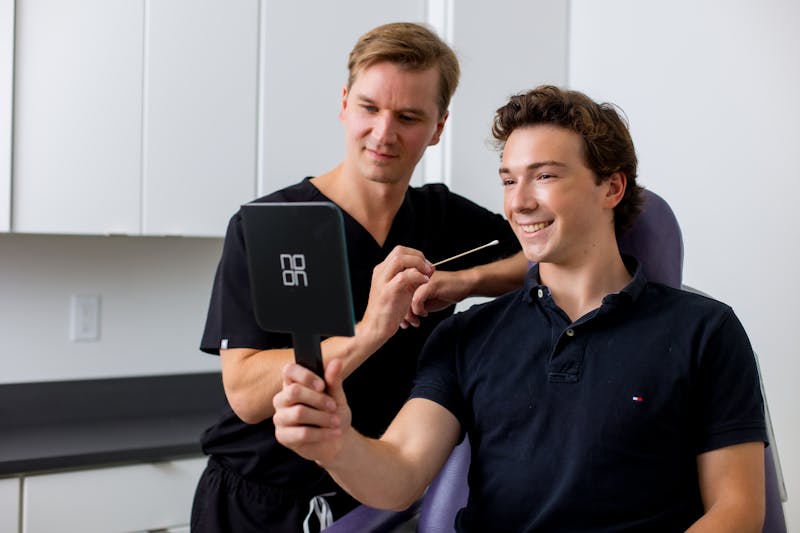 Dr. Tower with male patient looking into mirror with a cotton swab