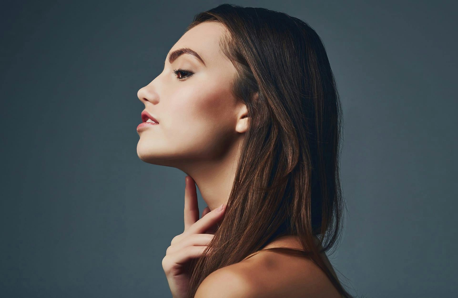 profile of a brunette woman touching her neck