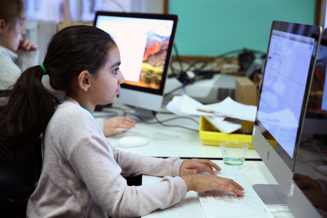 A Middle School student in front of a desktop computer working on coding as part of a Middle School club
