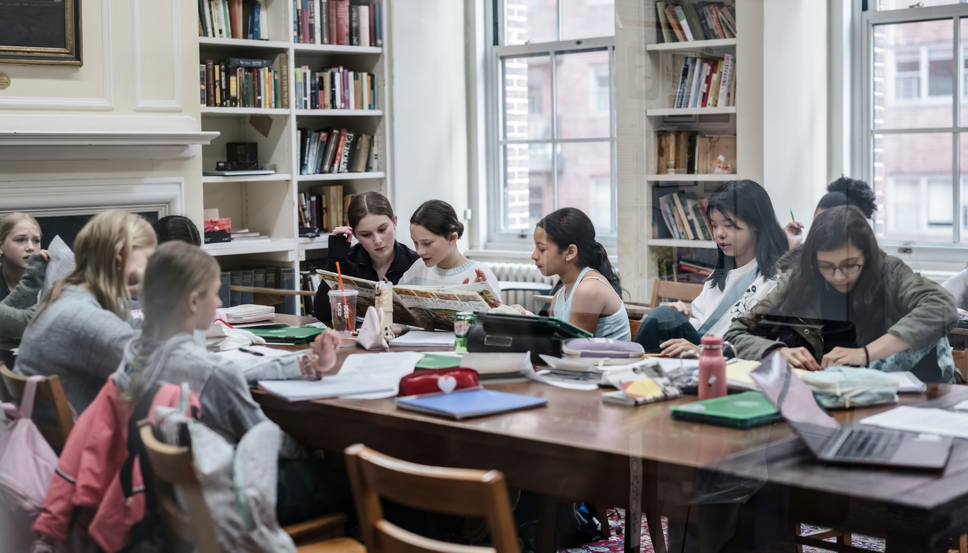 A group of middle school students sitting around a seminar table as part of their club meeting