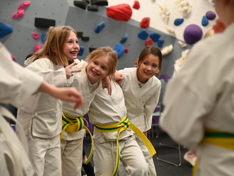 A group of lower school students in white tai chi outfits with yellow belts as part of the Brearley afterschool program.