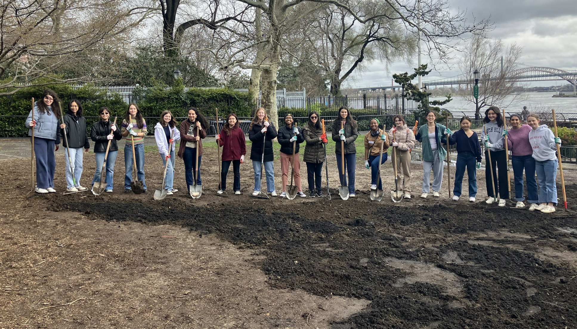 A group of upper school students posing with shovels in Carl Schurz Park as part of the community engagement work