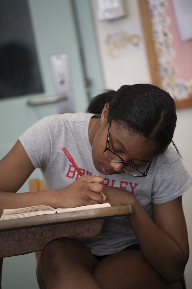 An Upper School students taking notes at her desk in the margins of her book.