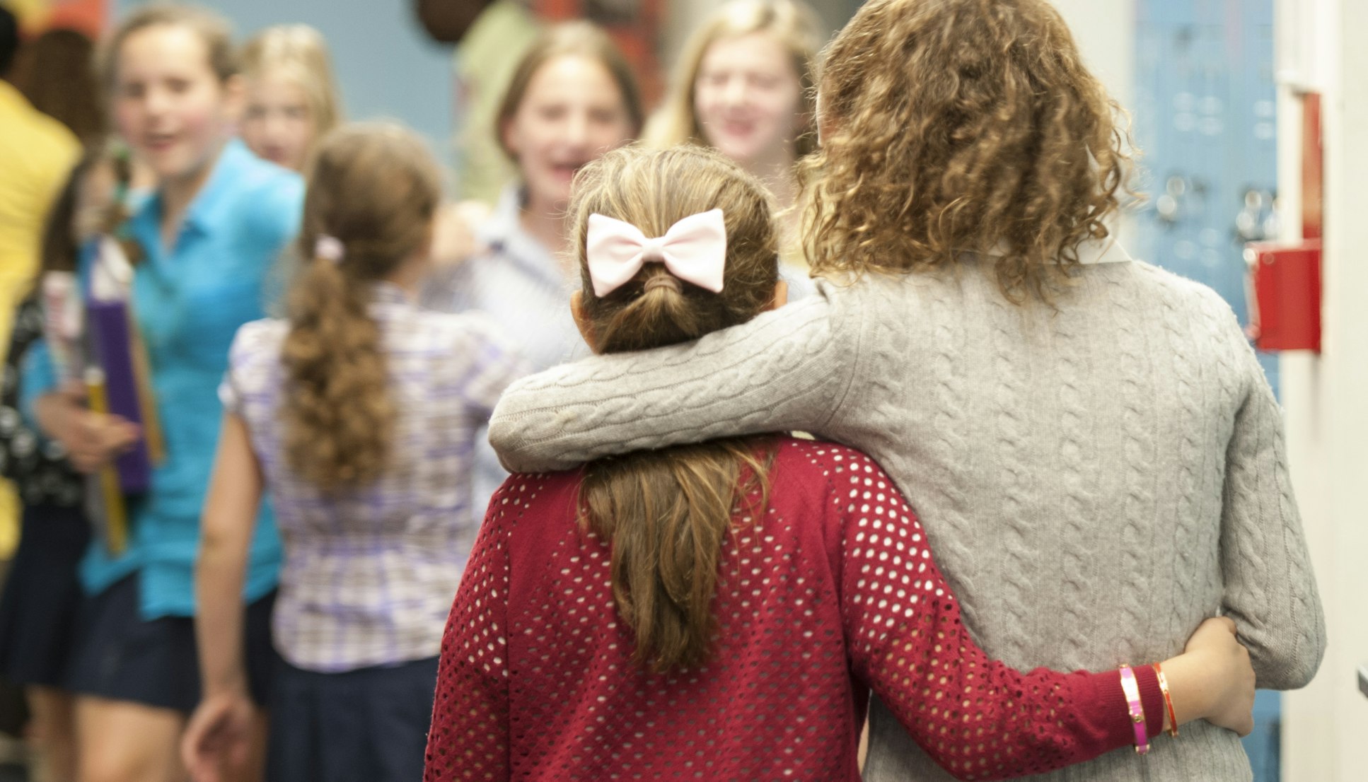 Two students with their backs to the camera but with their arms around each other.