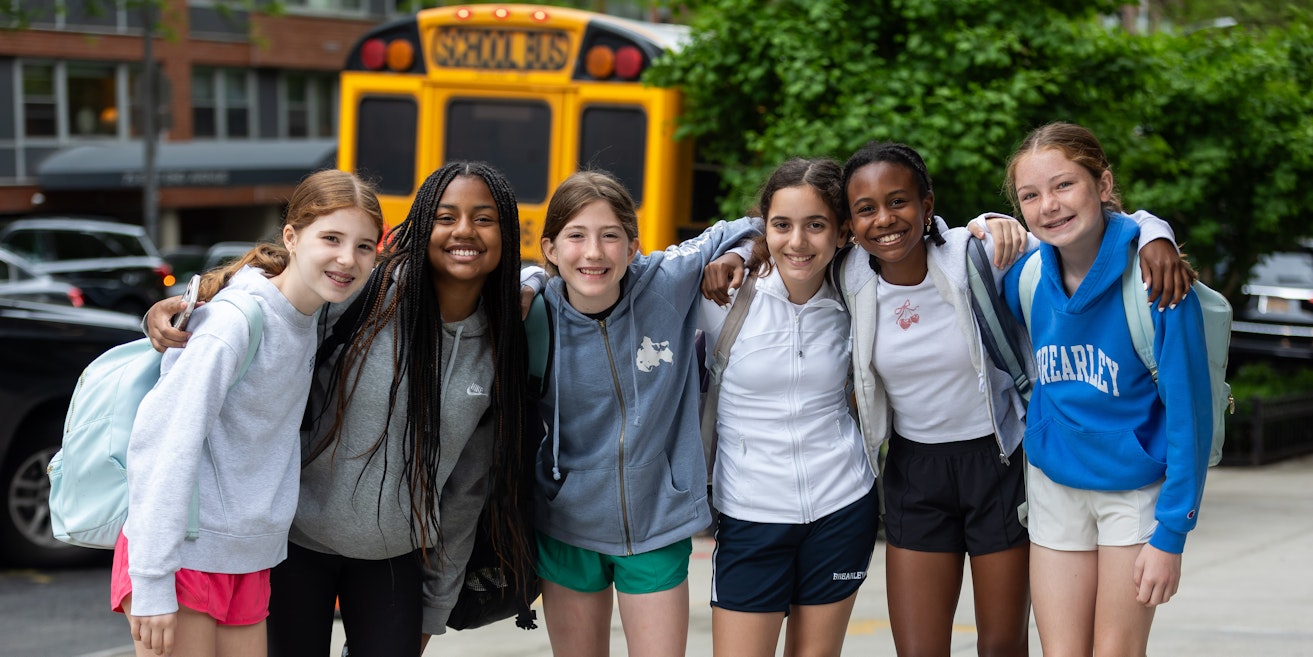 A group of six middle school students posing with their arms around each other smiling for the camera