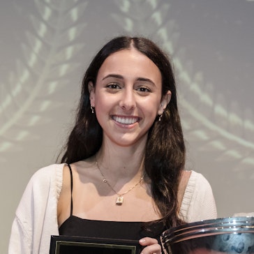 A senior holding a plaque presenting her with an athletic award