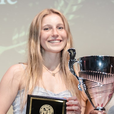 A senior holding a plaque presenting her with an athletic award