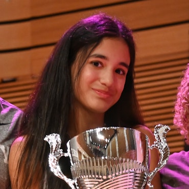 A student holding an Athletic Award whcih is a very large silver cup with two handles on each side