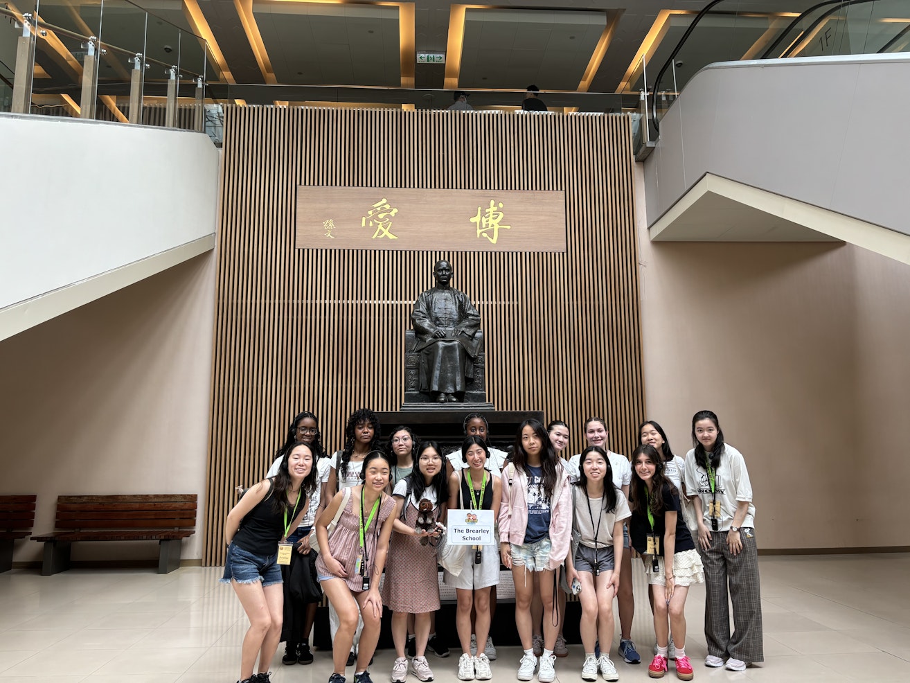 Upper School students in Taiwan visiting a school and posing in front of a statue