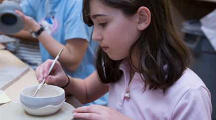 A middle school student working on a ceramics project.