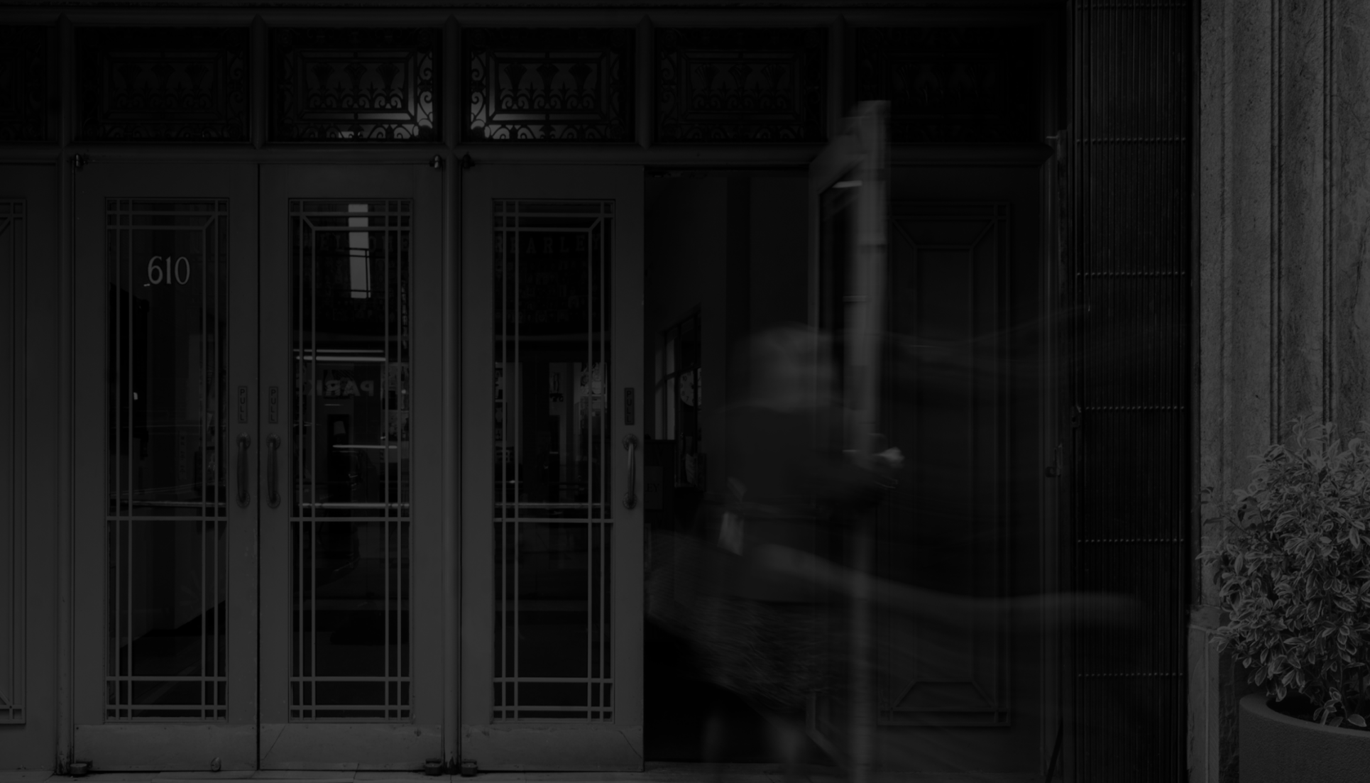 A timelapse photo of someone entering the doors of the 610 building