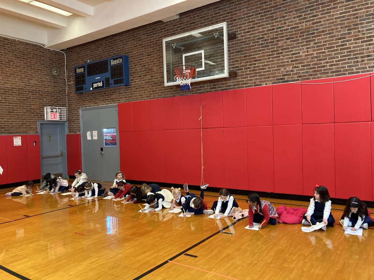 Students sit on the floor of the 610 gym as they mark their progress on papers for their 610 building tour.