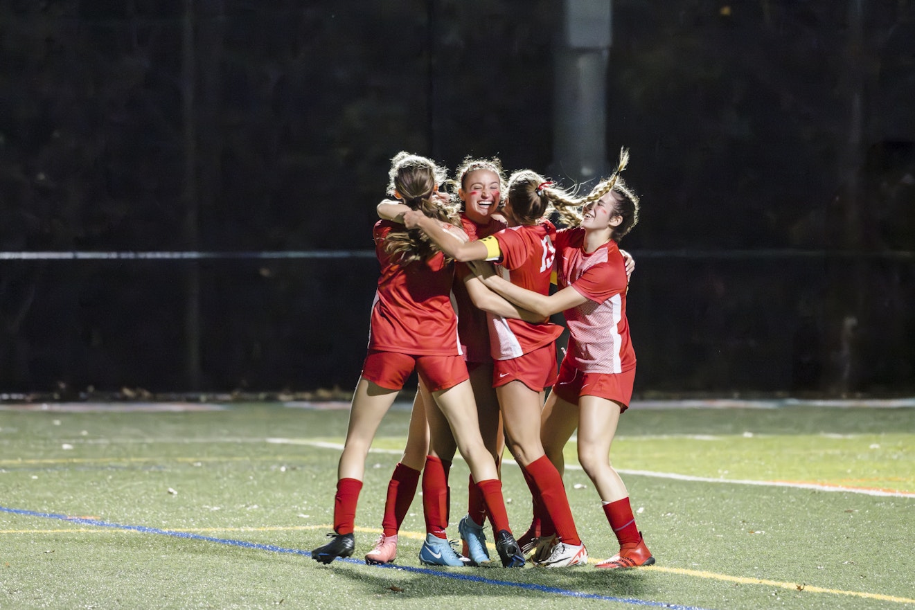 Members of the Varsity Soccer team cheering in a group after scoring a goal at the NYSAIS championship.