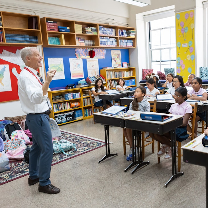 Fifth grade teacher animatedly making a point to his class of middle school students who are listening carefully.