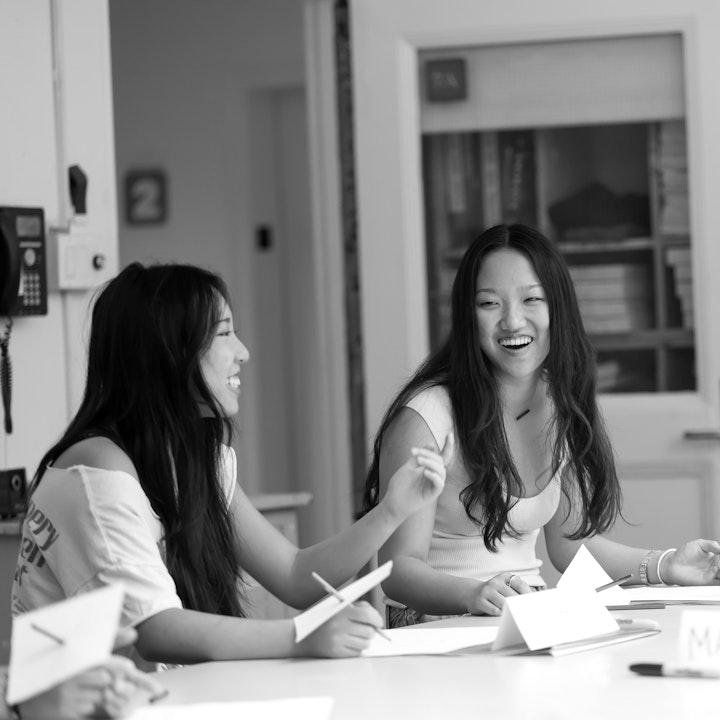 Two upper school students smiling and laughing as they collaborate on school work together