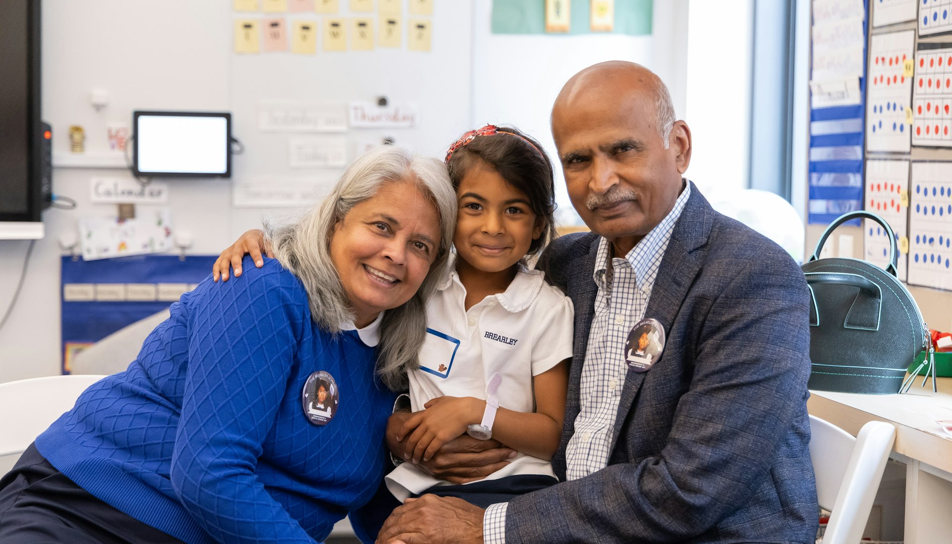 Grandparents smiling and hugging their granddaughter on Grandparents' and Special Friend's Day