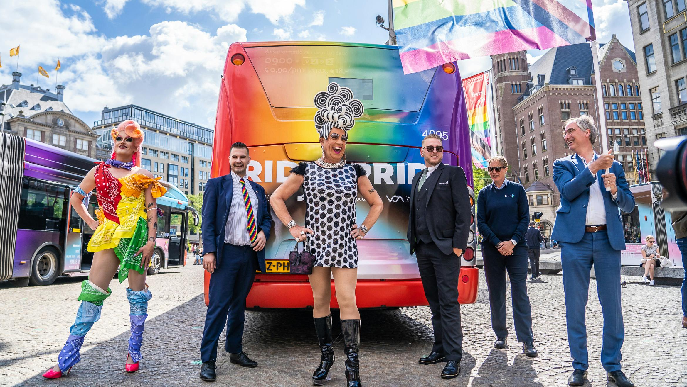 Dragqueens staan bij de regenboosbus van EBS