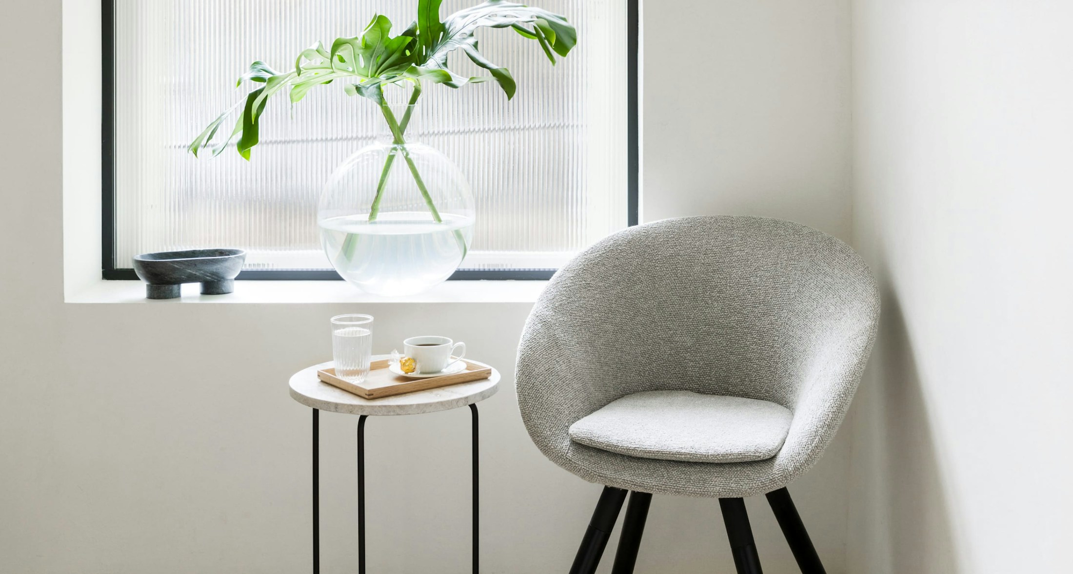 Chair in corner next to small table with glass of water and tea
