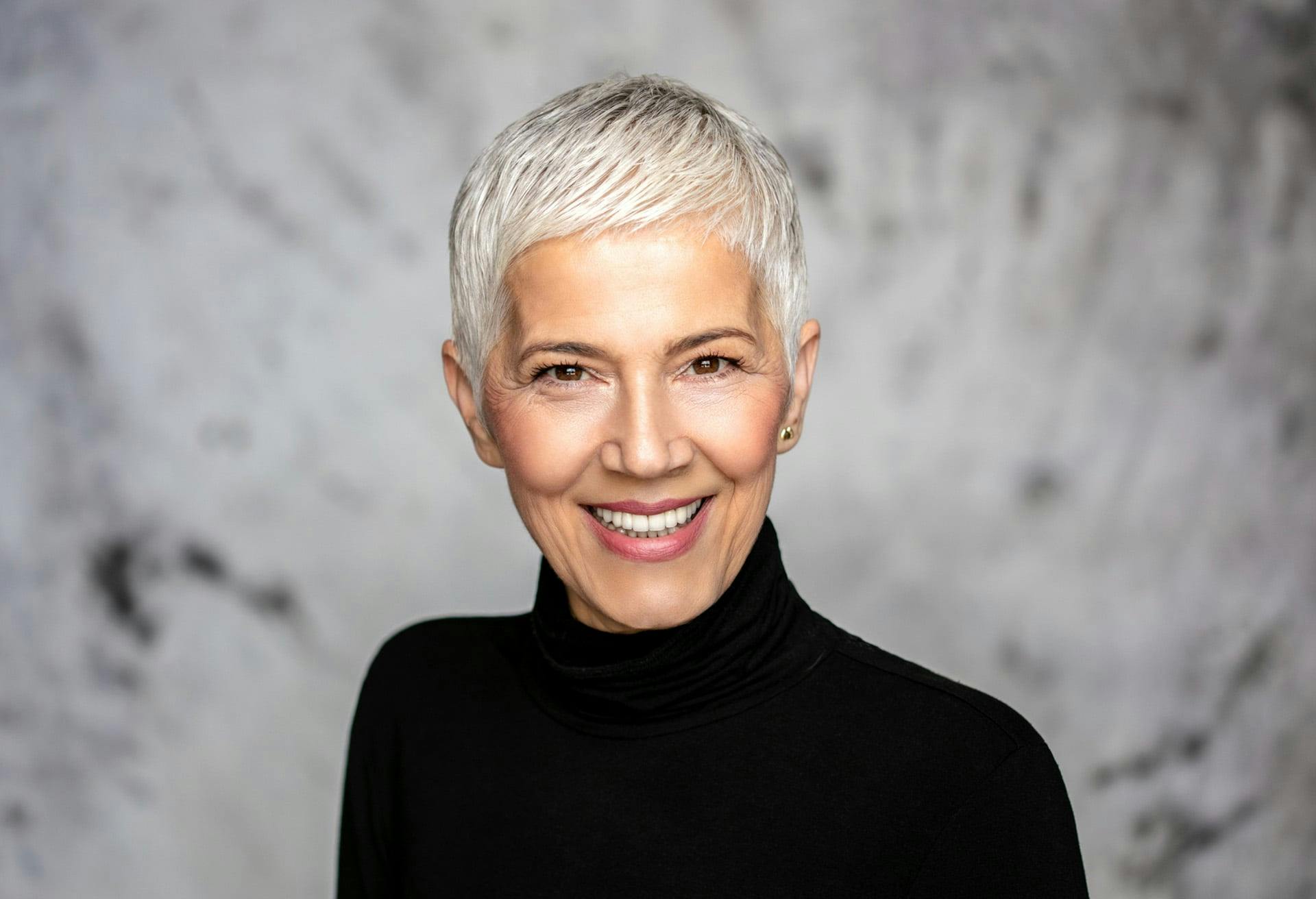 Older woman with very short hair smiling