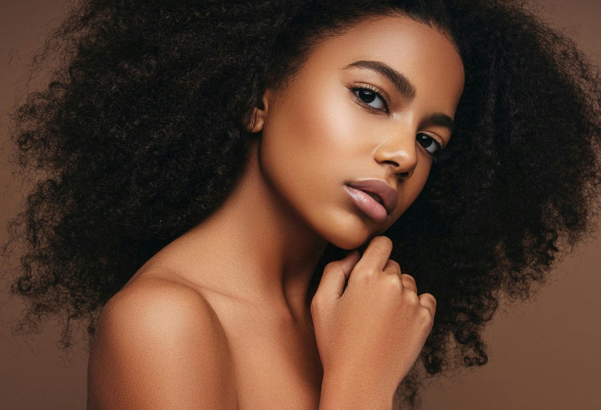 Woman with very curly hair with her hand on her chin