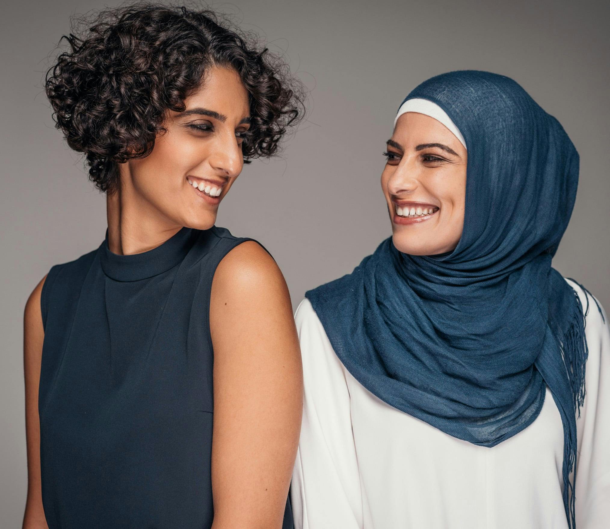 one women in a hijab smiling at another woman