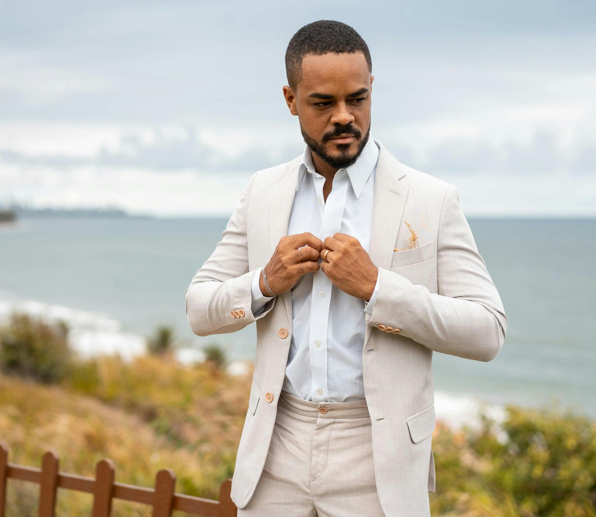 there is a man in a suit standing by the ocean