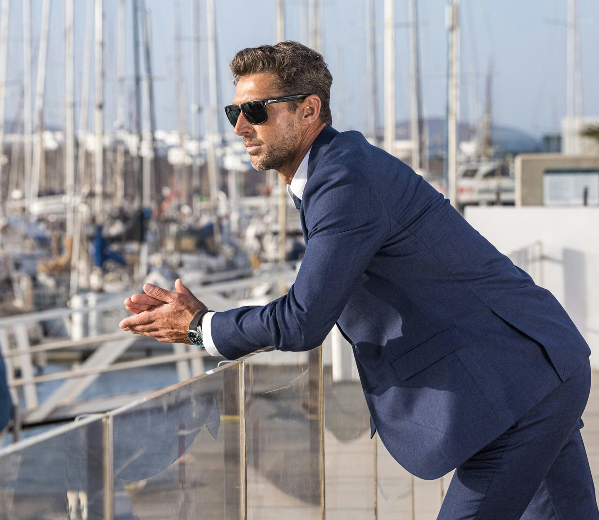there is a man in a suit and sunglasses leaning on a railing