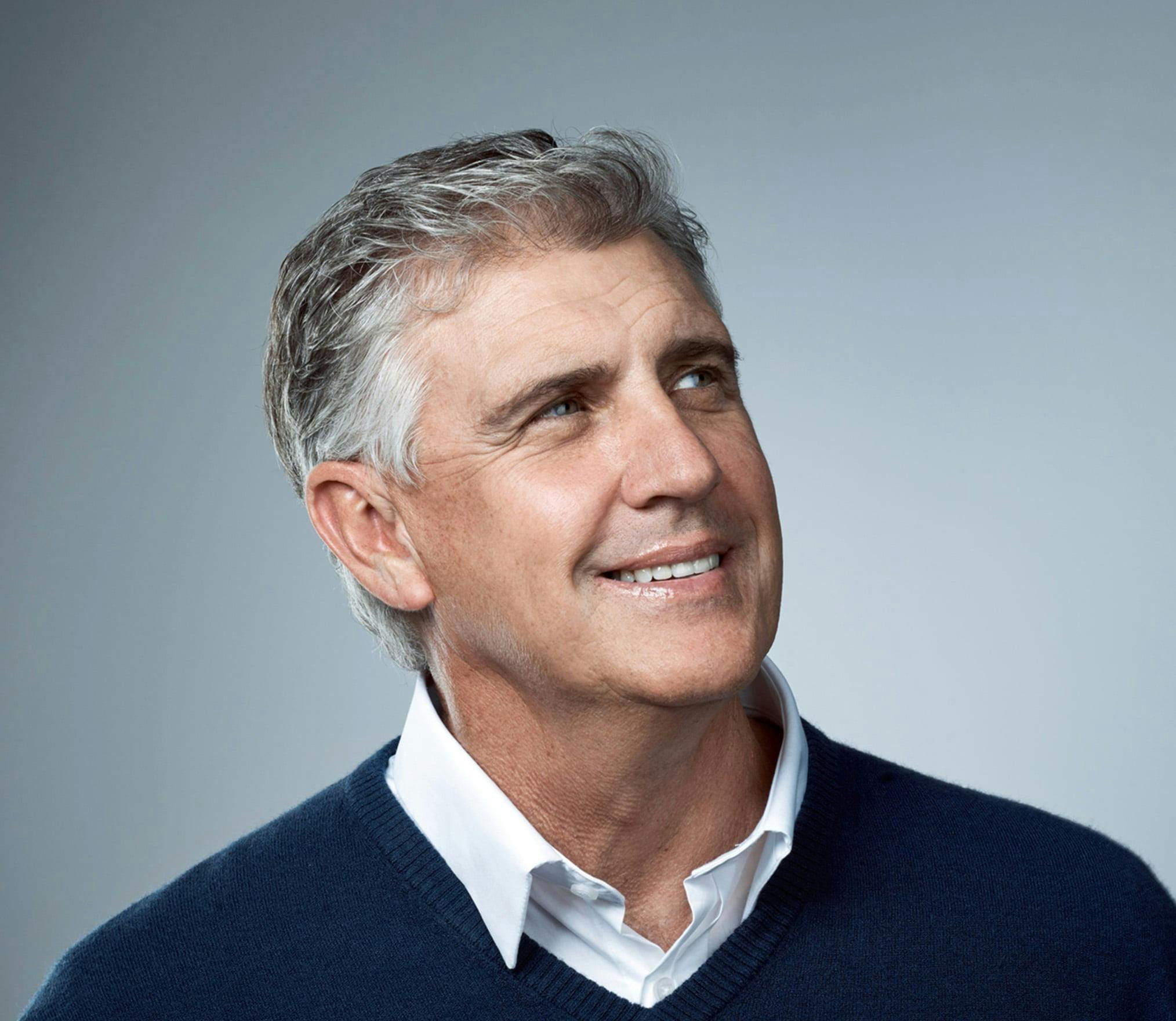 man with gray hair and a blue sweater looks up