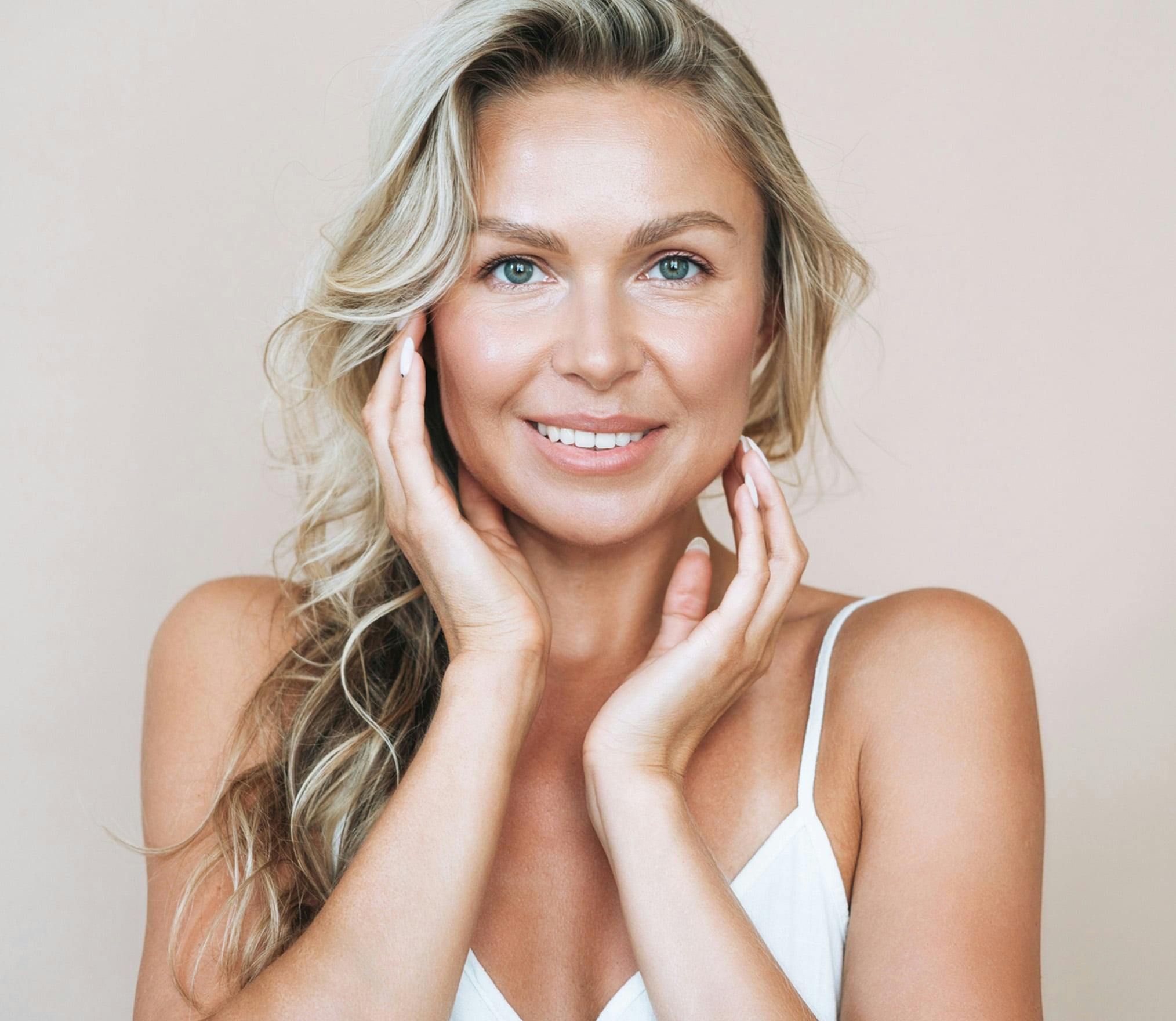 woman smiling holding face