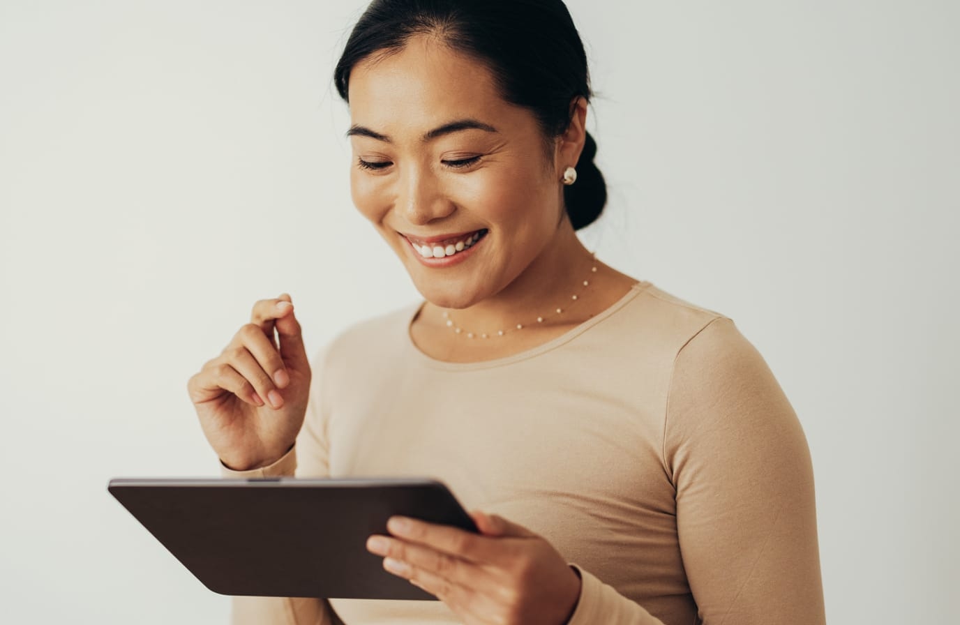 Smiling woman holding and looking at tablet