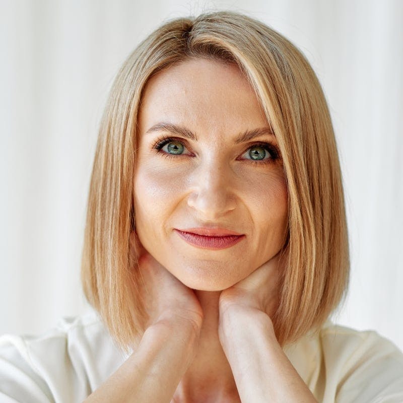 Woman with blonde short hair with her hands on her neck