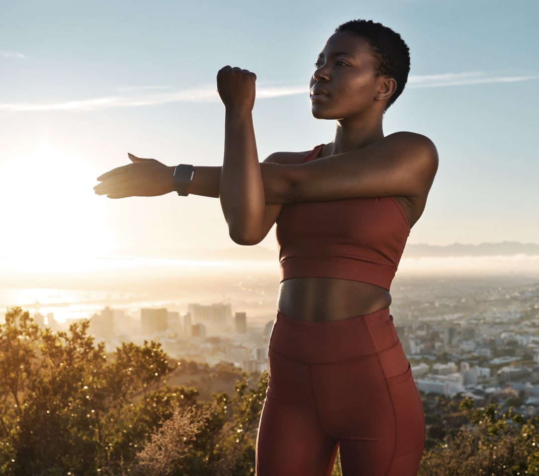 Woman wearing activewear with a stunning cityscape backdrop during sunset.