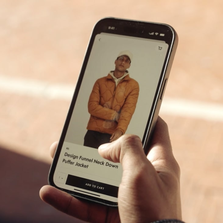 A person holding a phone with a screen showing an item being added to a cart