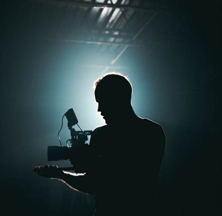 A silhouette of a man holding a camera in front of a light source