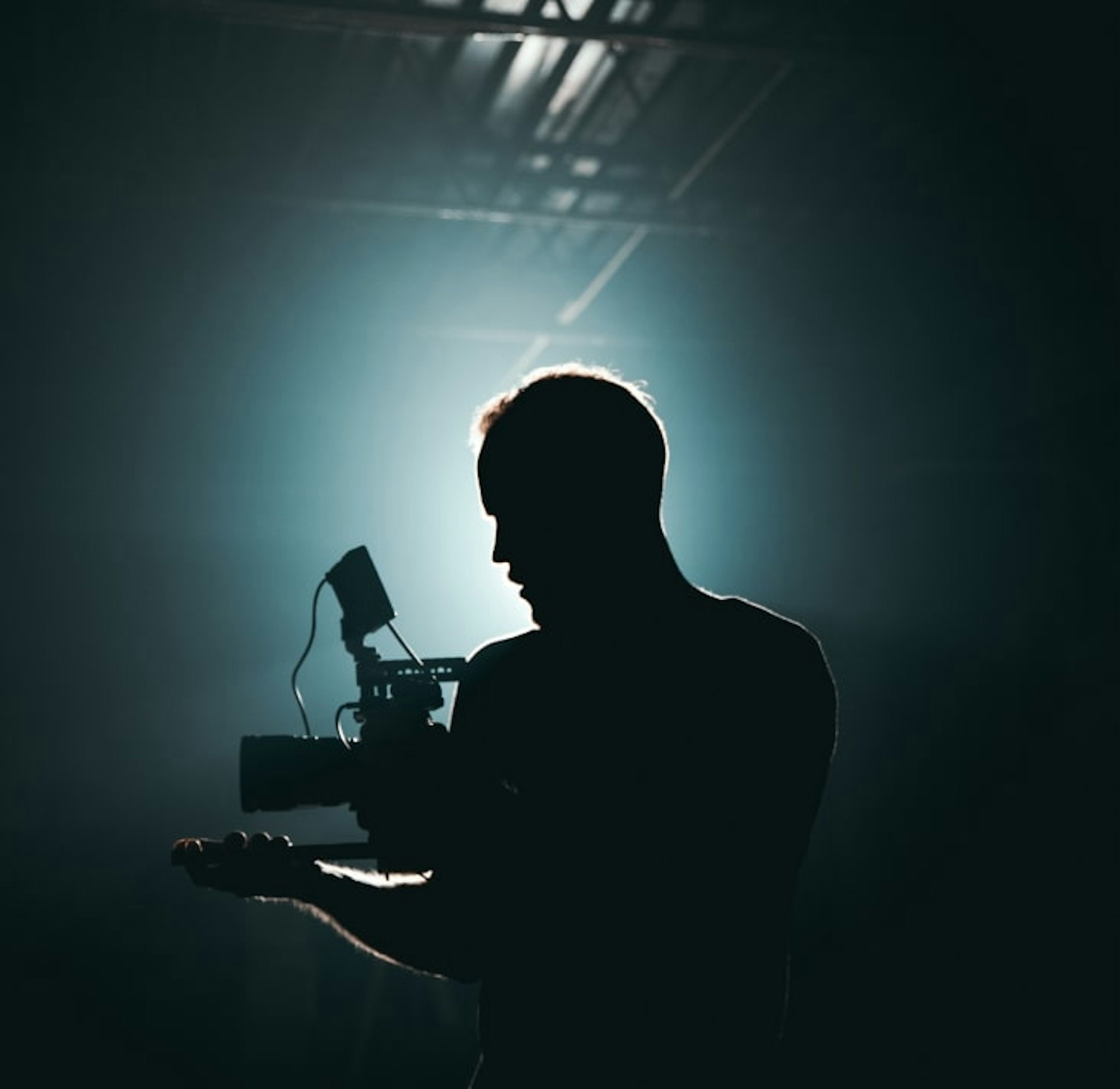 A silhouette of a man holding a camera in front of a light source